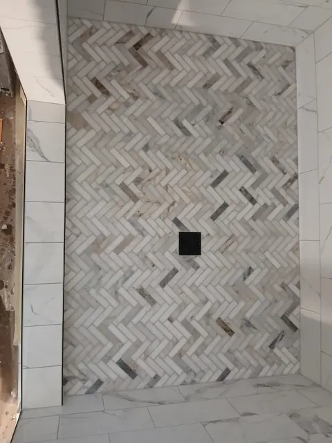 Walk-in shower with herringbone marble tile accent wall and black drain fixture, Kings Mountain Tile project in North Carolina