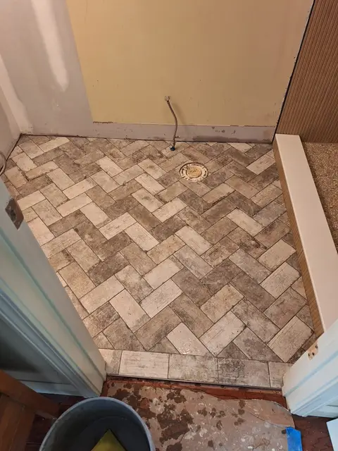 Herringbone brick-pattern tile shower floor before grouting, Kings Mountain Tile project in North Carolina