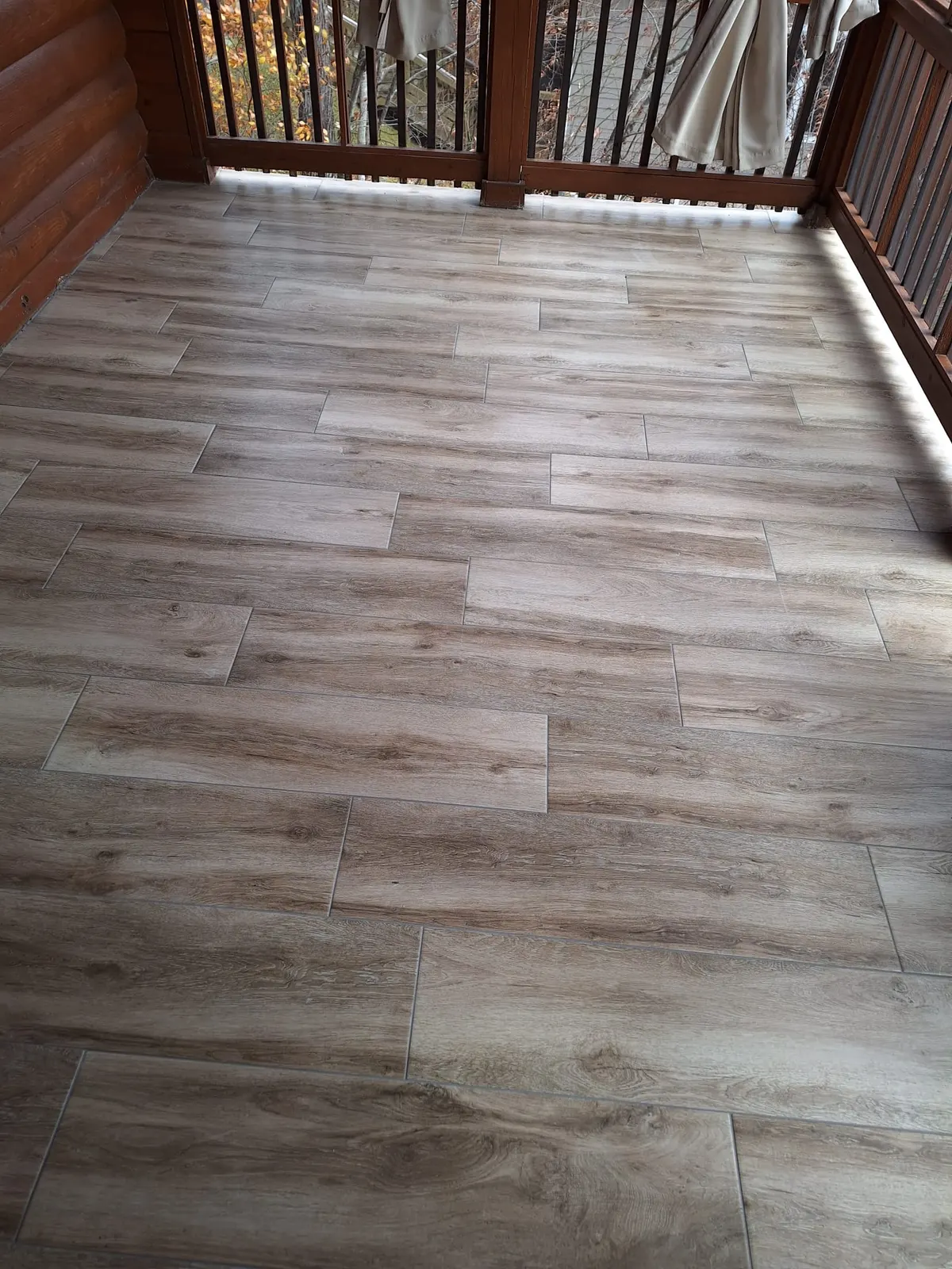 Gray wood-look vinyl plank flooring on a covered porch, Kings Mountain Tile project in North Carolina