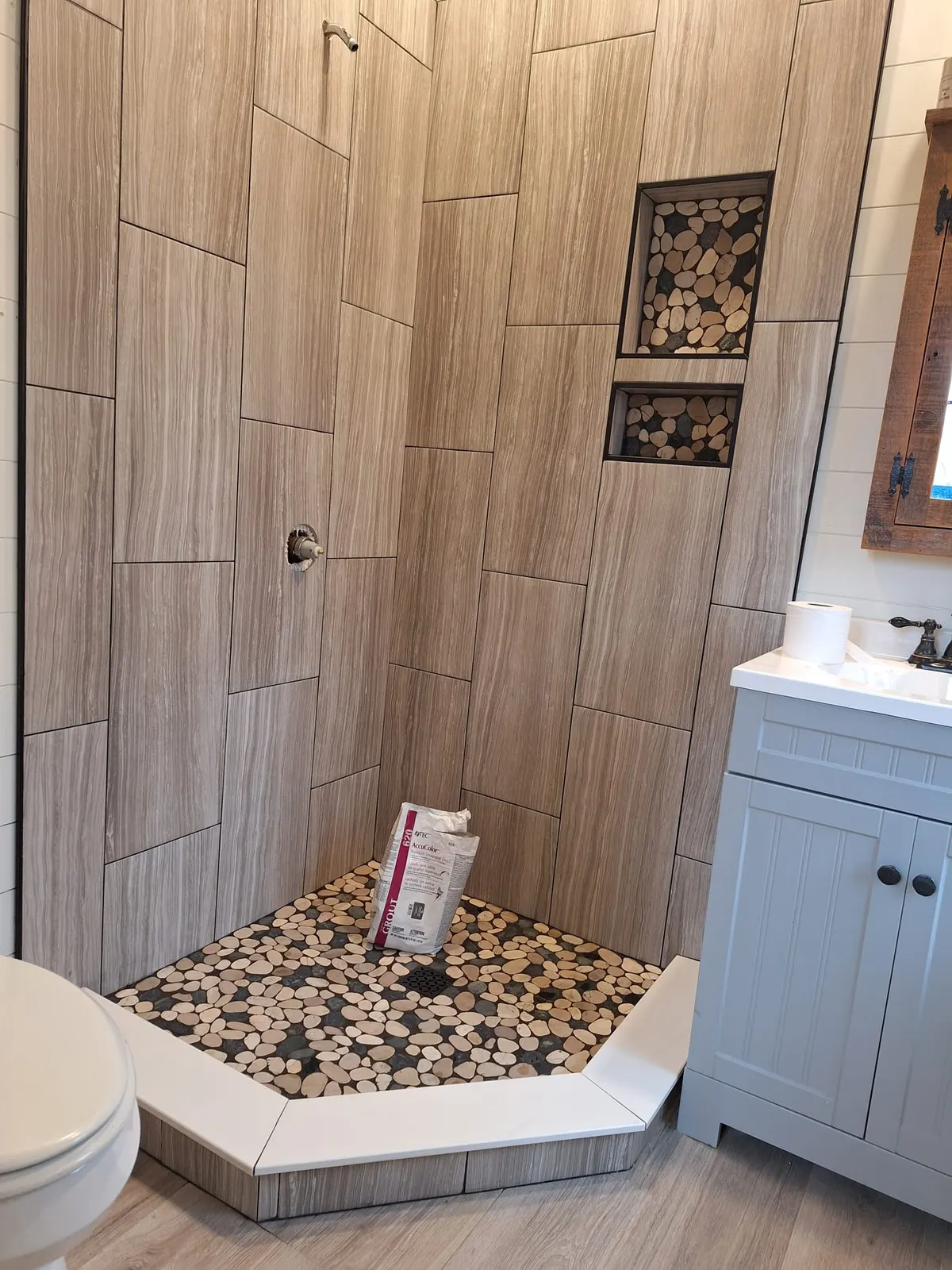 Vertical wood-look tile shower with pebble floor and decorative niches, Kings Mountain Tile project in North Carolina