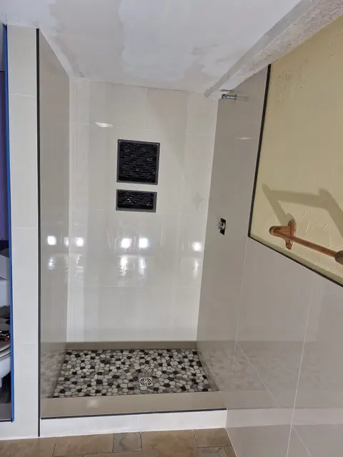 Tiled shower with white wall tile, two recessed niches and pebble floor, Kings Mountain Tile project in North Carolina