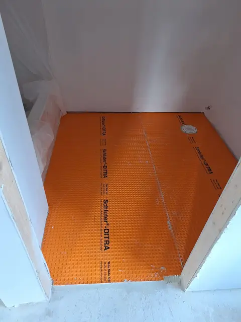 Orange waterproofing membrane applied on a shower base before tile