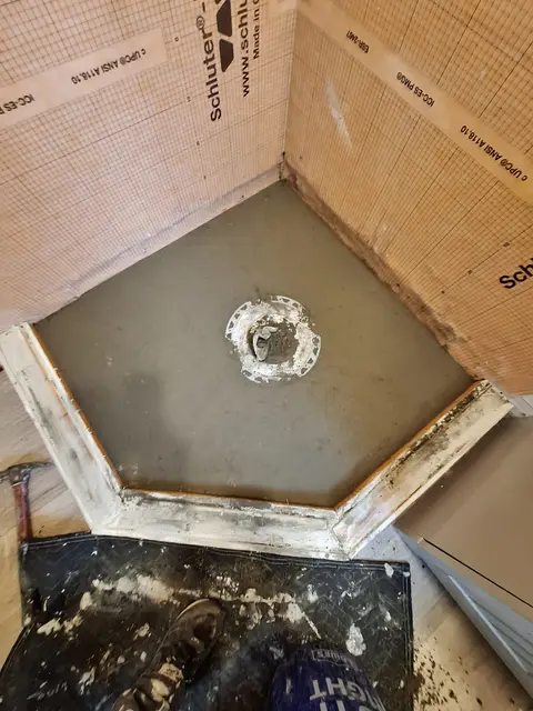 Shower pan with sloped mortar bed and drain during construction