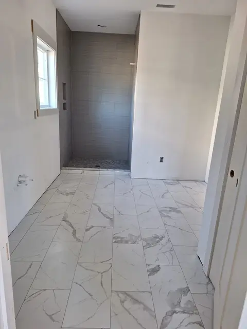 Marble-look tile floor in a bright hallway leading to a shower, Kings Mountain Tile project in North Carolina