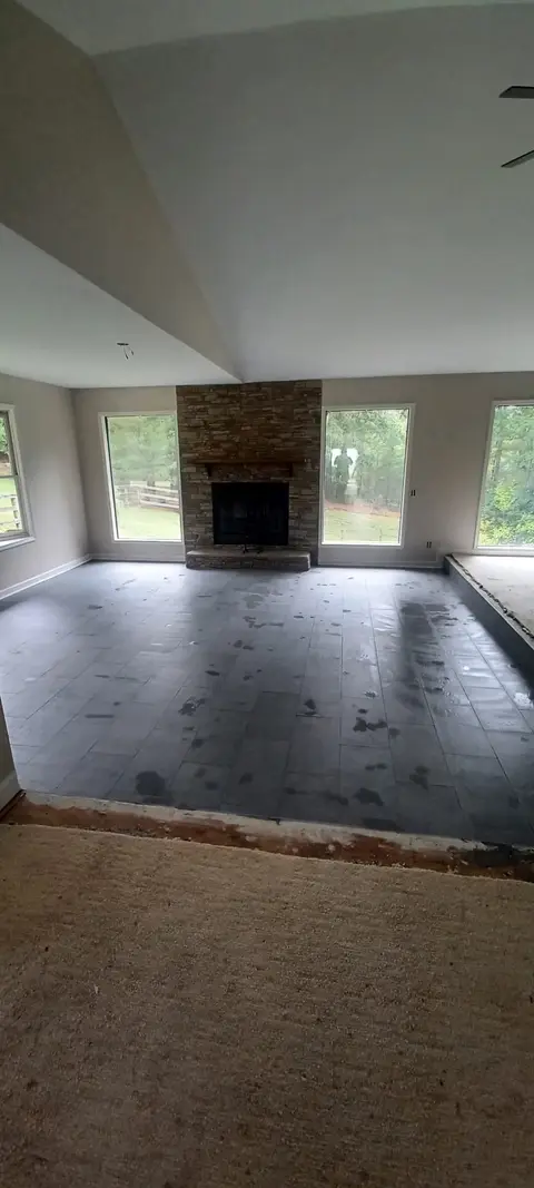 Living room tile floor installation in progress near a stone fireplace, Kings Mountain Tile project in North Carolina