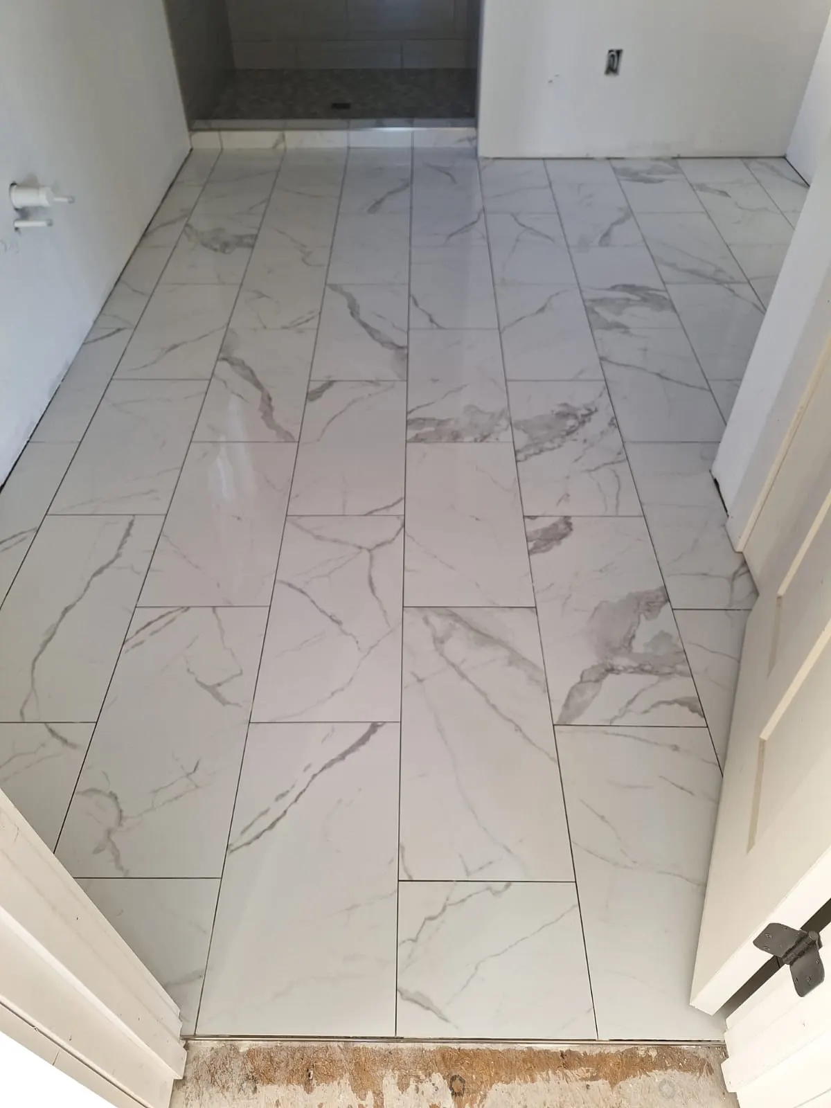 Large-format marble-look porcelain tile floor installed in a bathroom, Kings Mountain Tile project in North Carolina