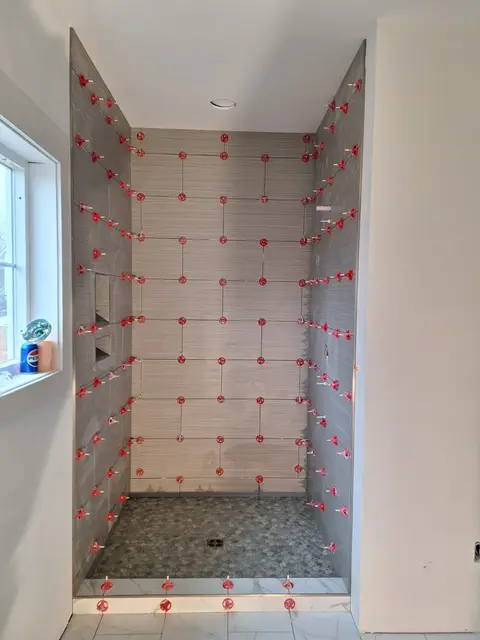 Shower walls with large tiles set with leveling spacers and pebble floor