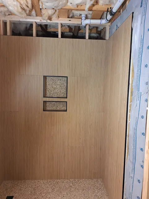 Shower walls with vertical wood-look tile and two pebble-tile niches, Kings Mountain Tile project in North Carolina