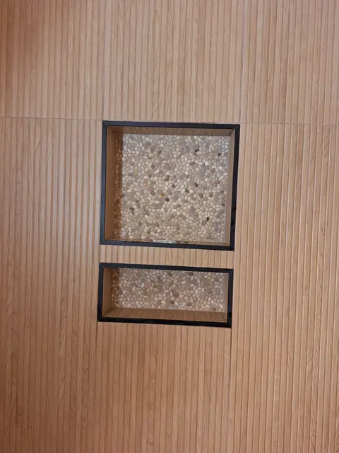Close-up of two pebble-tile niches set into a wood-look tile shower wall, Kings Mountain Tile project in North Carolina