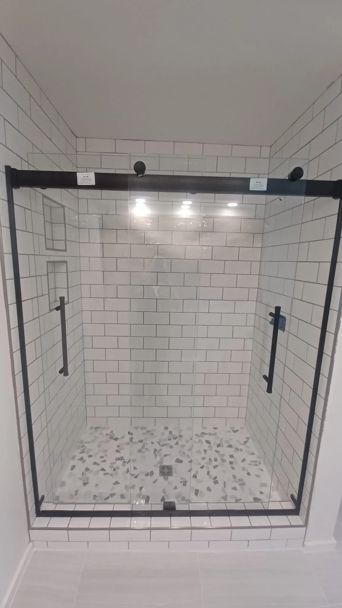Frameless glass shower with white subway tile and mosaic floor, Kings Mountain Tile project in North Carolina