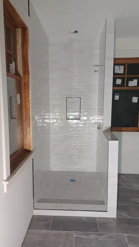 Shower wall finished with glossy white tile and a recessed niche, Kings Mountain Tile project in North Carolina