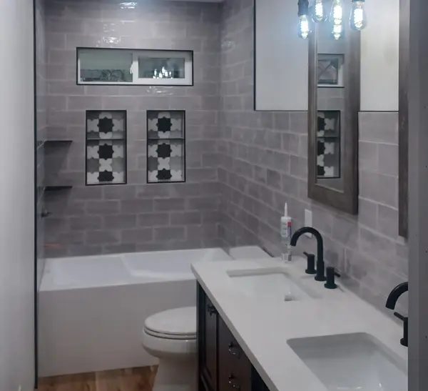 Remodeled bathroom with gray subway tile, patterned accents and double vanity