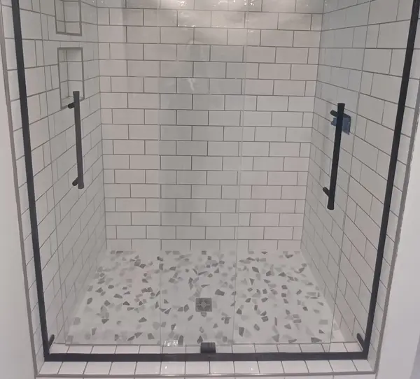 Walk-in tiled shower with subway tile walls and pebble floor
